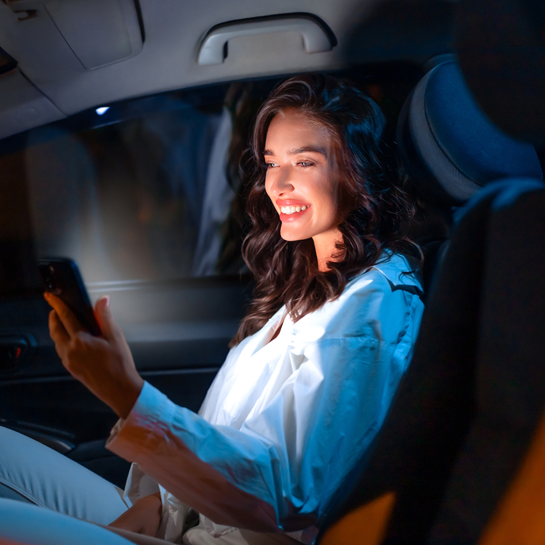 Woman enjoying her luxury limo ride while using her phone during a night out in San Jose