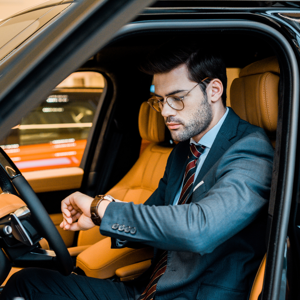 Business man checking his watch inside a luxurious Oakland airport limo, ensuring timely airport transportation.